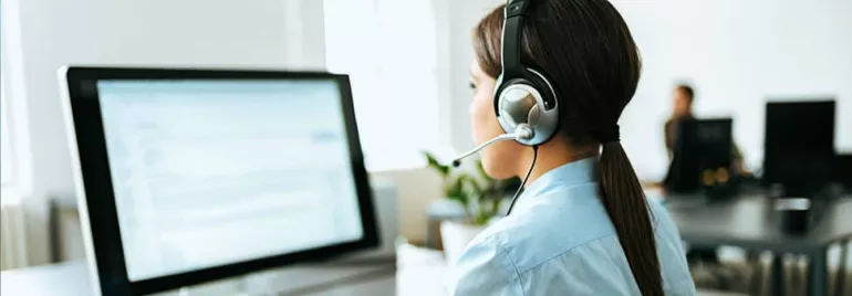 Person wearing a headset working at a computer.