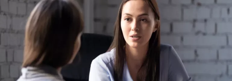 Asian woman in serious discussion with another female in an office setting