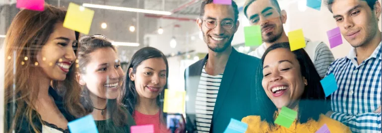 Group of people looking at sticky notes on a glass board