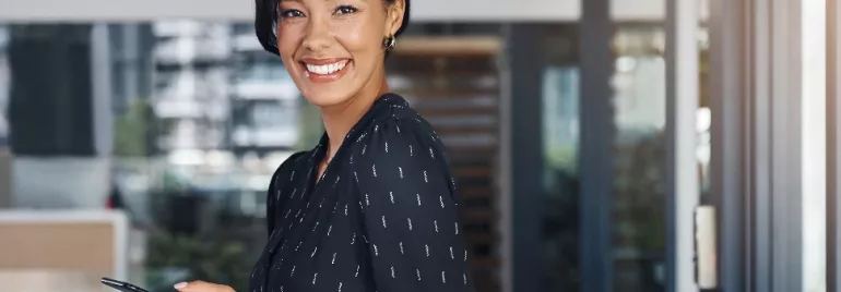 Person smiling while holding a phone in an office setting.