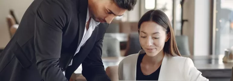 Two people discussing a project on a laptop in a cafe
