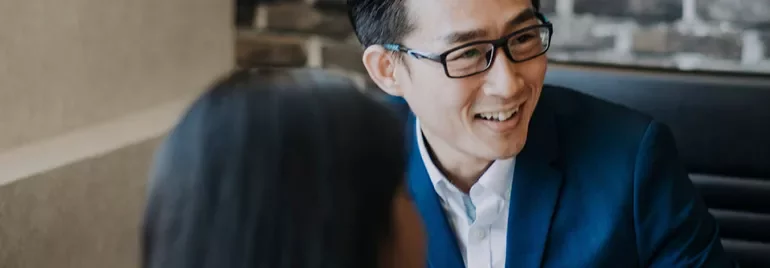 Person in a suit smiling and talking with a colleague.