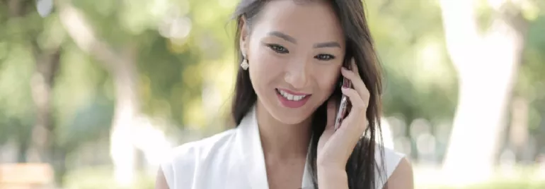 Person smiling while using a phone outdoors