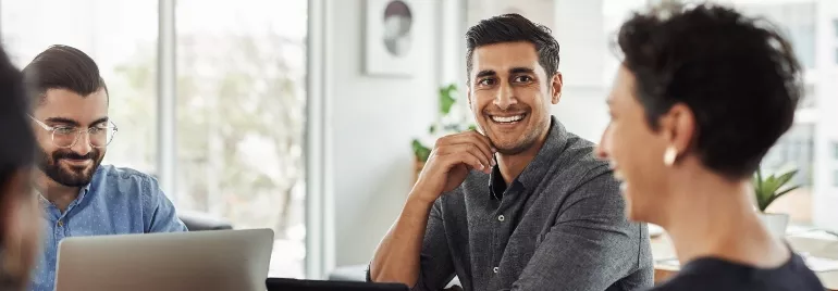 A group of people having a meeting in an office, smiling and conversing.