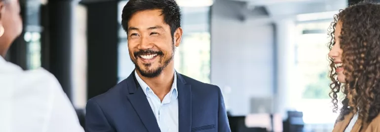 在辦公室裡，一個人與同事握手，微笑交流。
