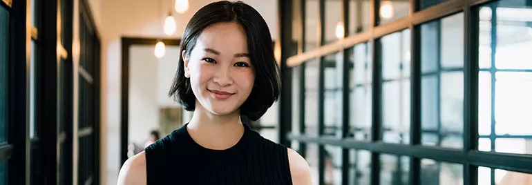 Person smiling in a modern office setting with glass partitions.