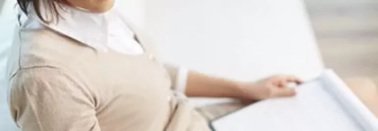 戴眼鏡的人正在閱讀筆記，手裡拿著筆。