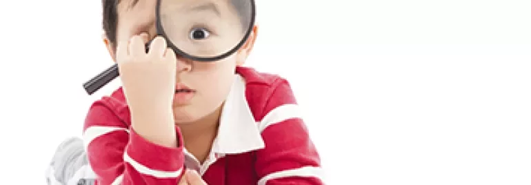 小孩用放大鏡觀看圖書。