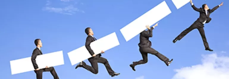 四人在草地上抬著一支向上的箭頭，象徵進步。