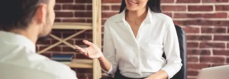 兩個人在辦公室交談，桌上有筆記本電腦和文件。