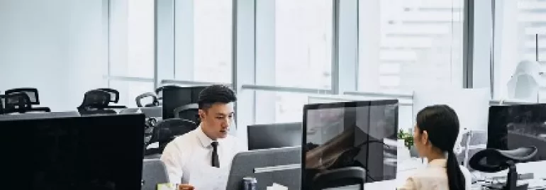 辦公室內兩人坐在電腦前工作。