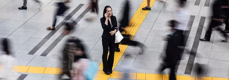 Person on phone in busy urban scene, surrounded by motion.