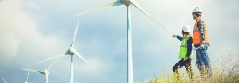 兩人在風力發電機旁的山坡上