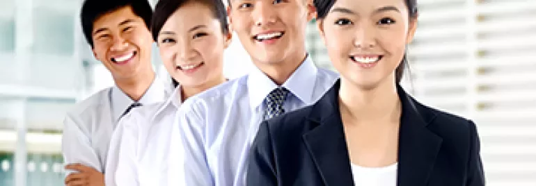 四人在辦公室微笑，身穿商業服裝。