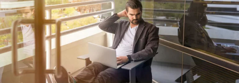 A person working on a laptop on a balcony.
