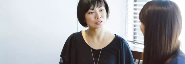 兩人坐在桌邊交談，一人看向另一人。