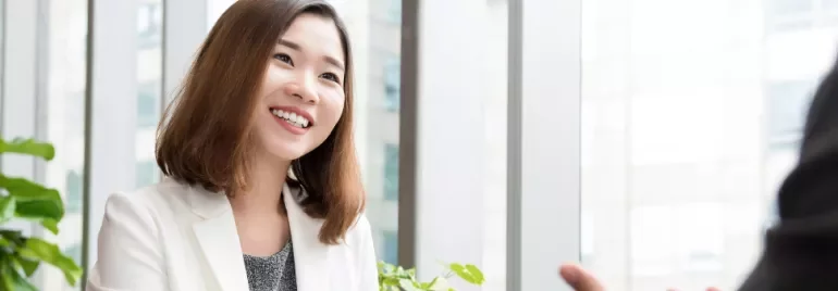 穿著白色外套的人在辦公室中微笑交流。