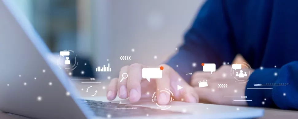 Hands typing on a laptop keyboard with digital icons nearby