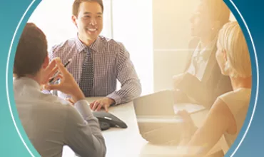 Four people smiling and talking in an office meeting