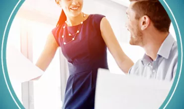 Two people in an office smiling at each other during a discussion