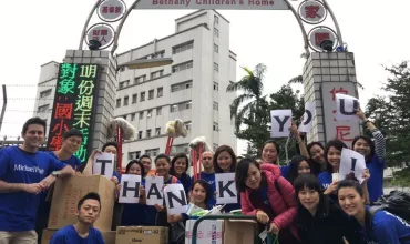A group of people posing in front of Bethany Children's Home, holding thank you signs.