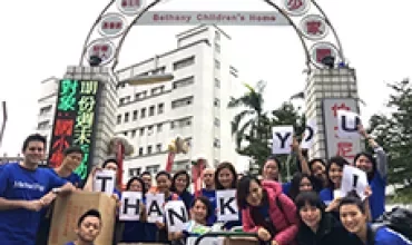 一群人在建築前揮舞著寫有感謝字樣的標語。