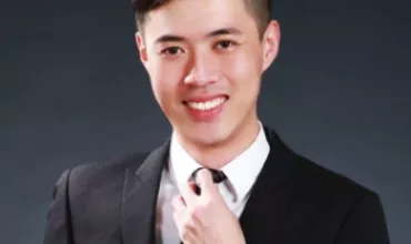Smiling person in a suit adjusting a necktie