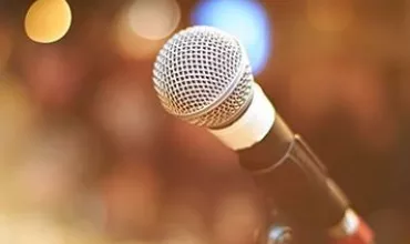 Microphone on stage with blurred lights in background.