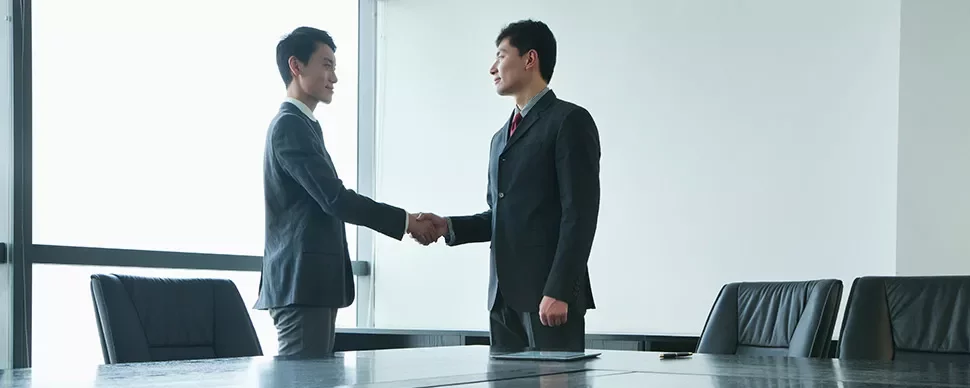 Two people shaking hands in a conference room