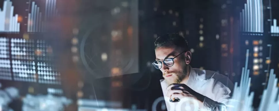 Person analyzing data charts on a computer at night