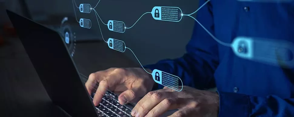 Hands typing on a laptop with blockchain icons visible.