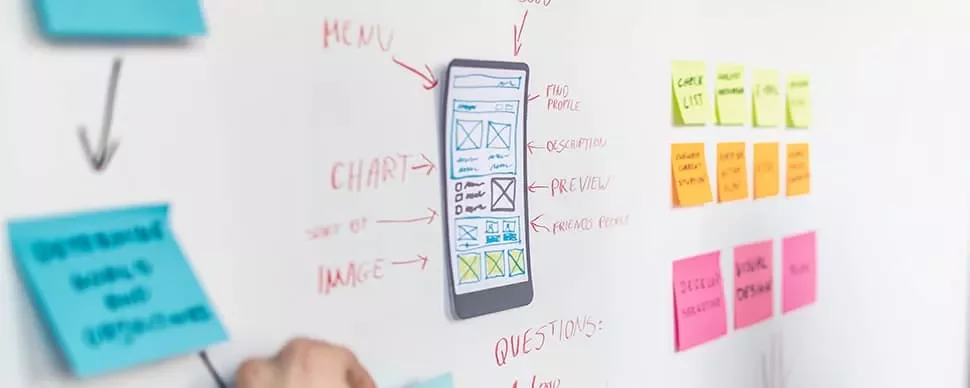 A whiteboard with a mobile interface sketch and sticky notes during a design meeting.