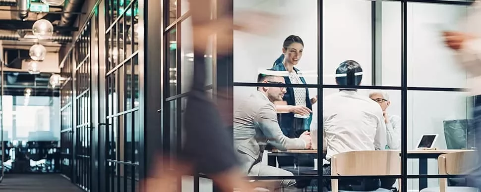 Group of people having a meeting in a glass-walled conference room.