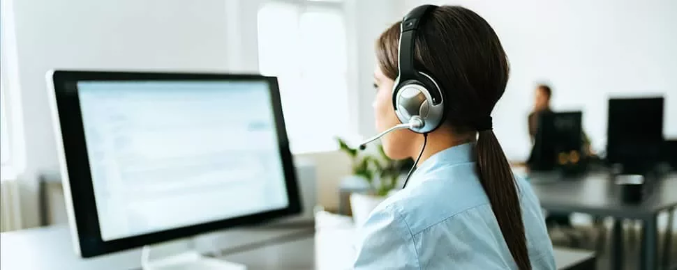 Person wearing a headset working at a computer.