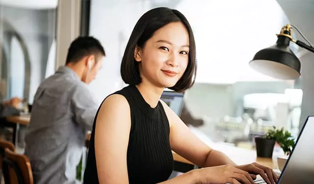 在咖啡廳工作的年輕人，面帶微笑坐在筆記本電腦前