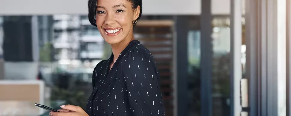 Person smiling while holding a phone in an office setting.