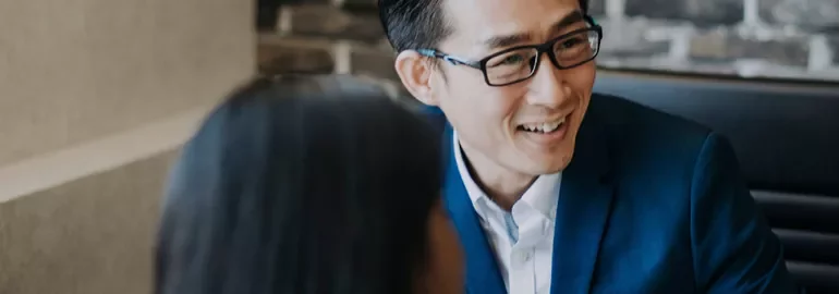 Person in a suit smiling and talking with a colleague.