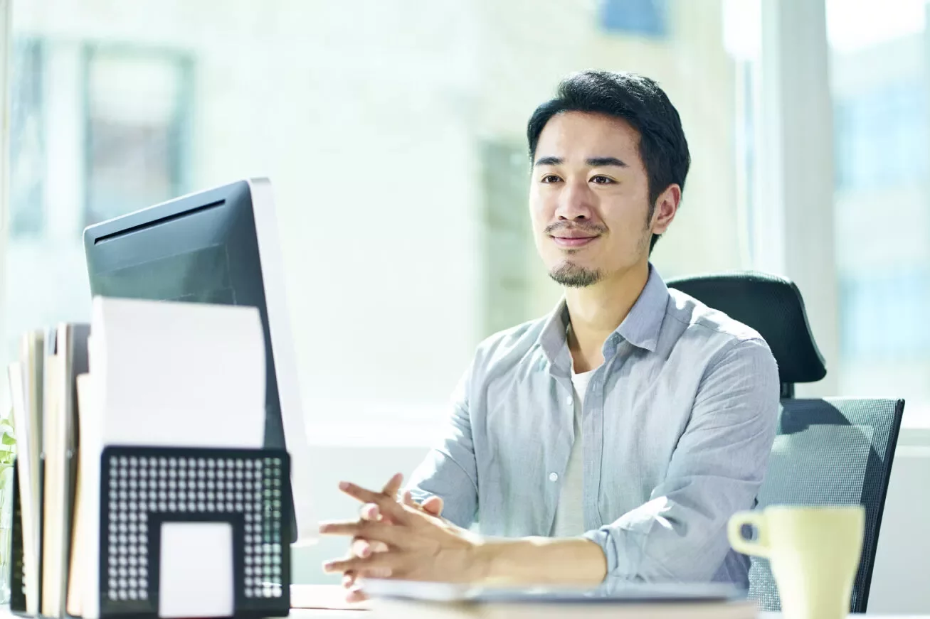 A professional sitting at a desk, smiling.