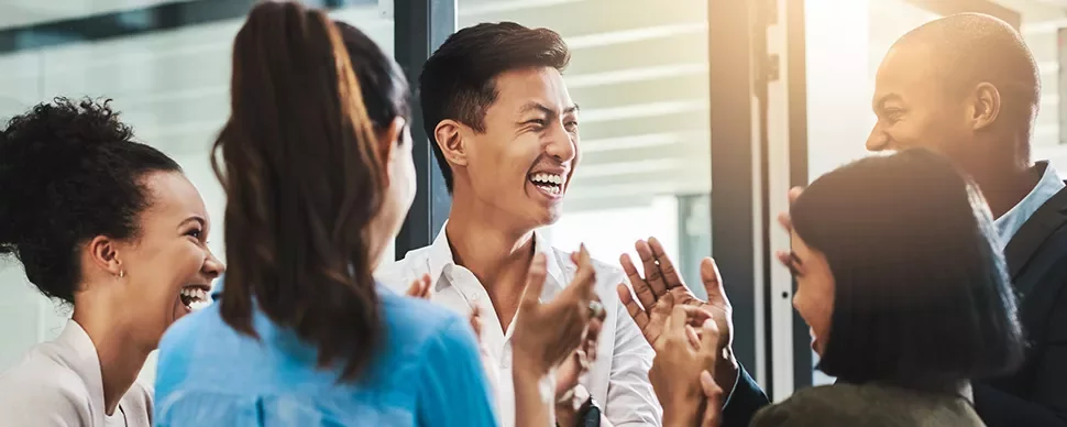 Group of people laughing and talking in an office