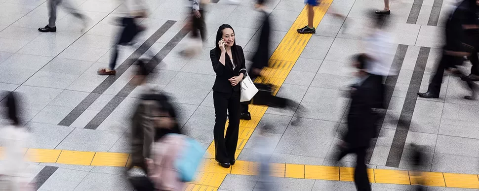 Person on phone in busy urban scene, surrounded by motion.
