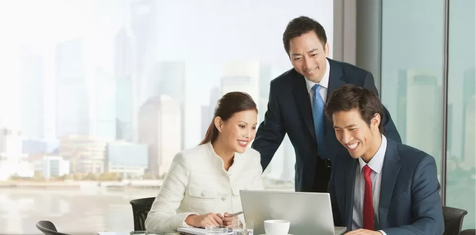 三人在辦公室中合作，共同使用筆記本電腦。