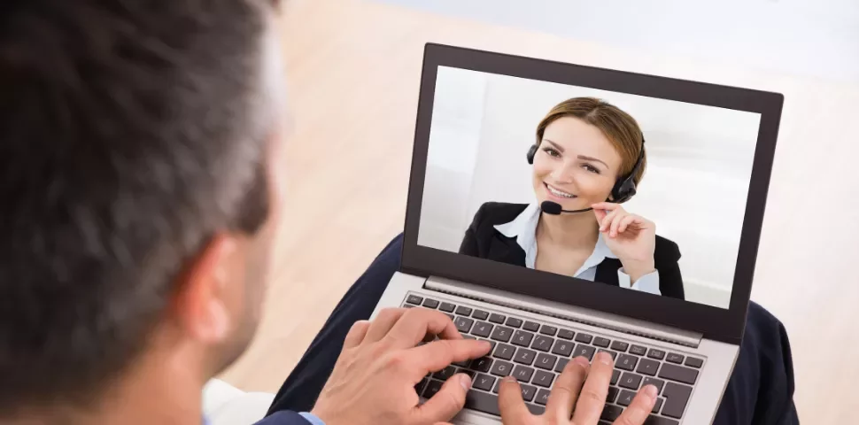 A person using a laptop for a video call, showing someone wearing a headset.