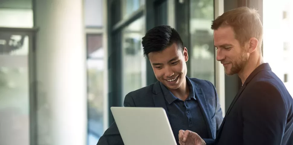 Two people looking at a laptop in an office