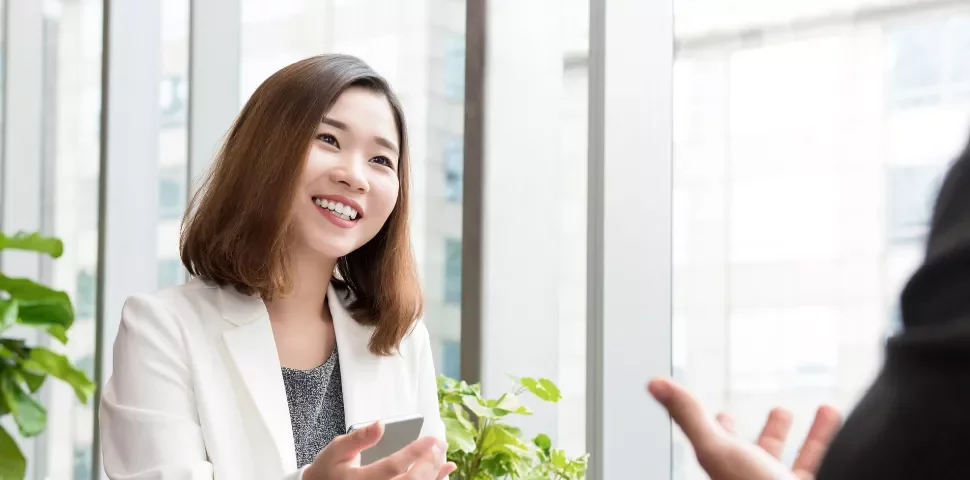 Person smiling during a meeting in a bright office.